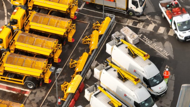 High-angle video frame showing a highways depot with gritters, MEWPs, and snow ploughs in Birmingham.