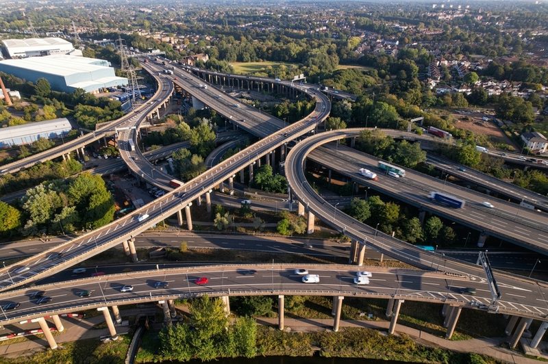 High-angle drone view of a multi-level motorway interchange and bridge structures with active traffic flow.