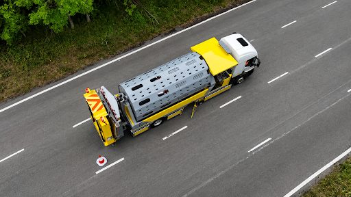 An aerial drone view of an automated cone laying vehicle operating on a dual carriageway highway.