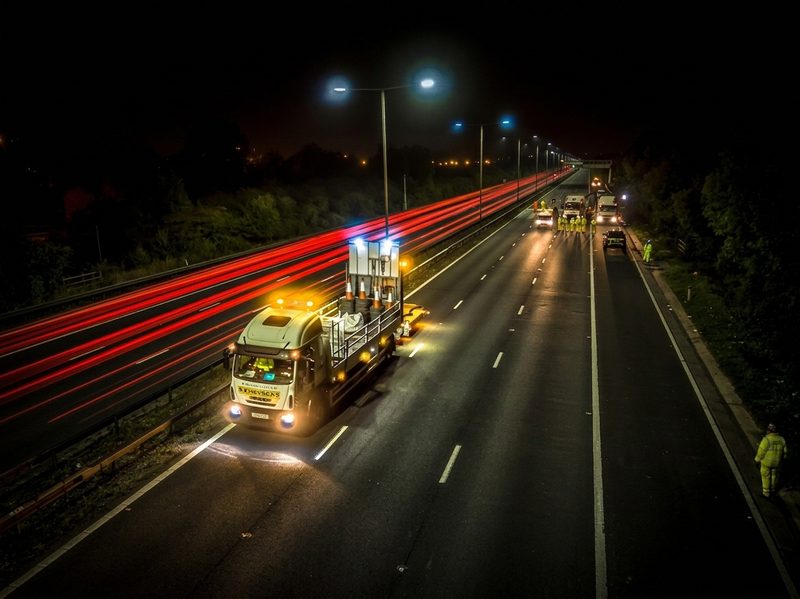 Long-exposure photograph of a Chevron Traffic Management vehicle on the M6 at night with red light trails.