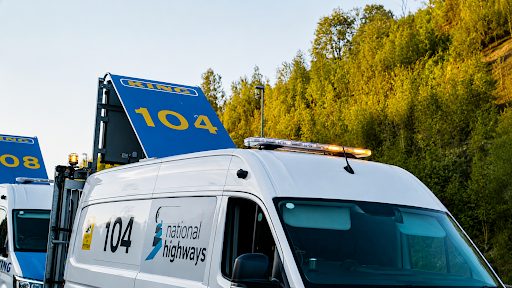 Close-up of a white National Highways maintenance van with amber beacon and blue signage on its roof.