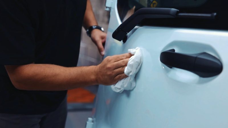 Video frame of a technician cleaning a vehicle panel for an illuminated Chapter 8 safety kit installation.