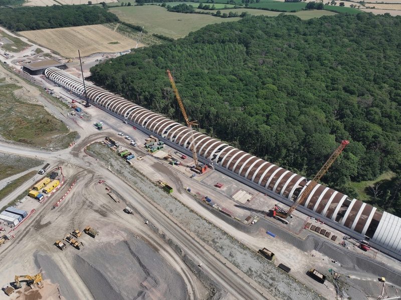 Drone view of a large arched tunnel structure under construction within a rural highway scheme.