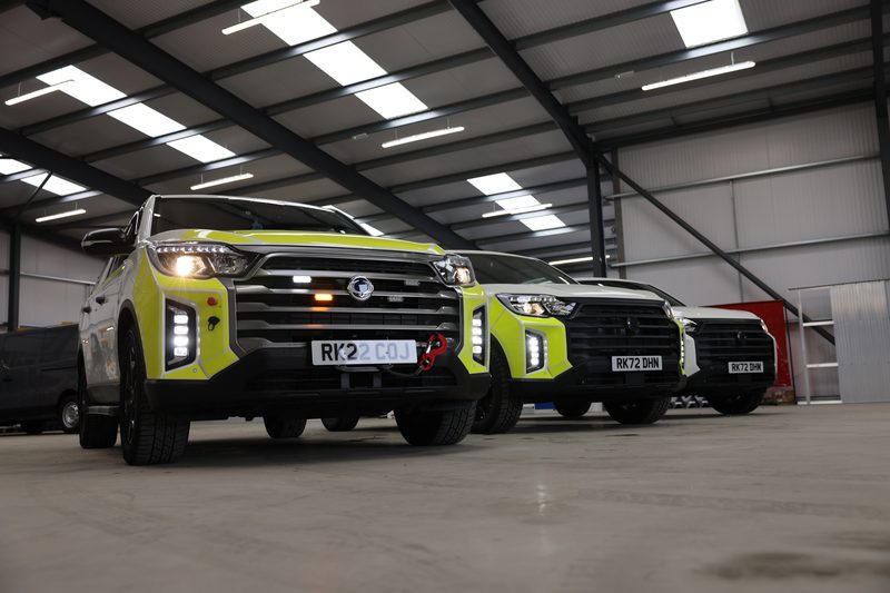 A row of highways fleet vehicles with high-visibility markings parked inside a large industrial depot building.