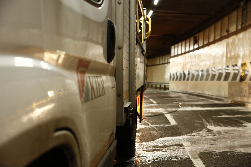 Close-up of a highways maintenance vehicle parked inside a brightly lit tunnel during cleaning and maintenance works.