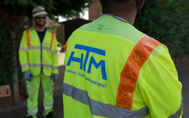 Close-up of a traffic management operative in high-visibility clothing on a highway site during the day.